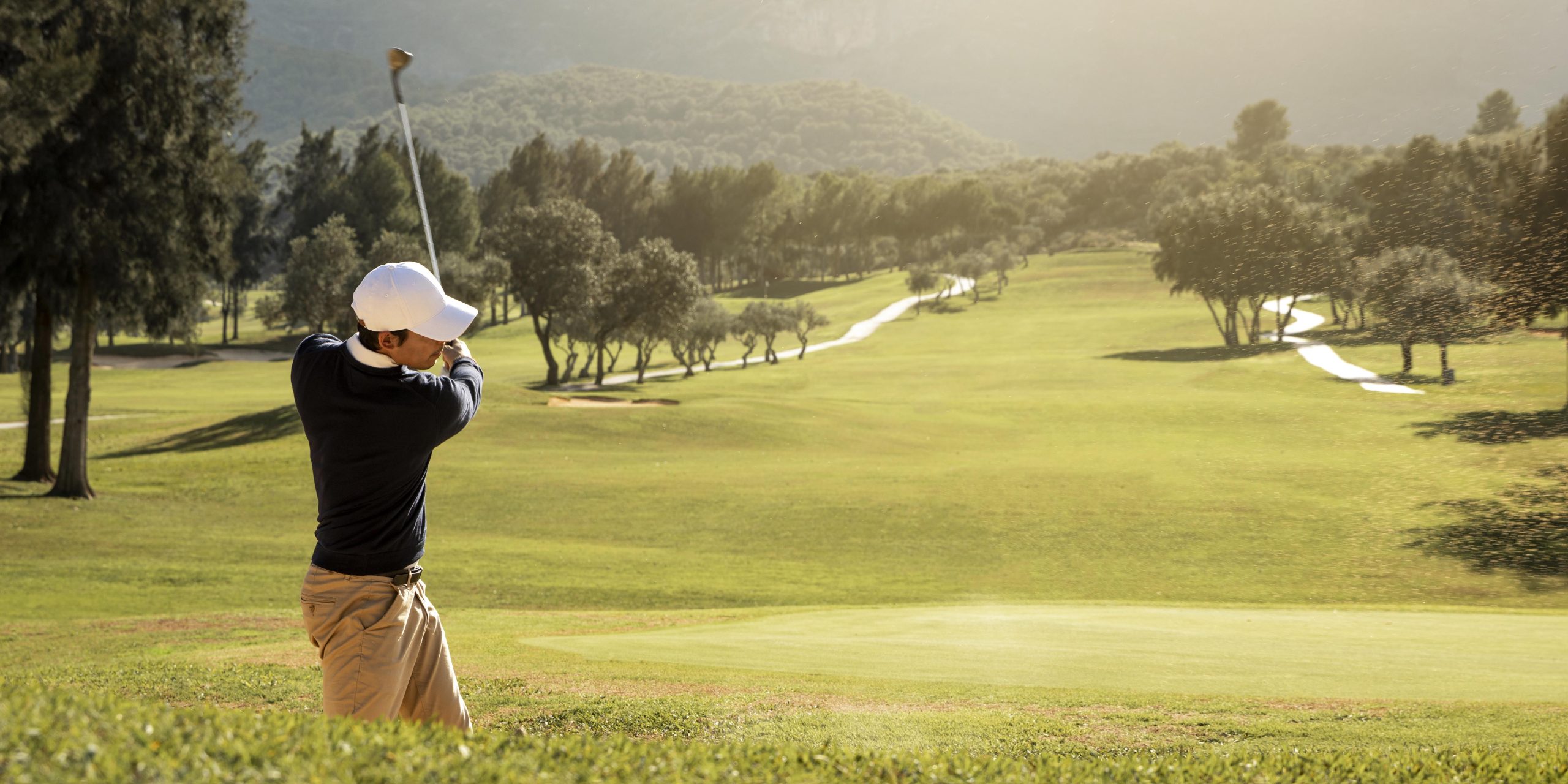 Golfista ejecutando un swing en un campo arbolado durante un torneo de golf para empresas