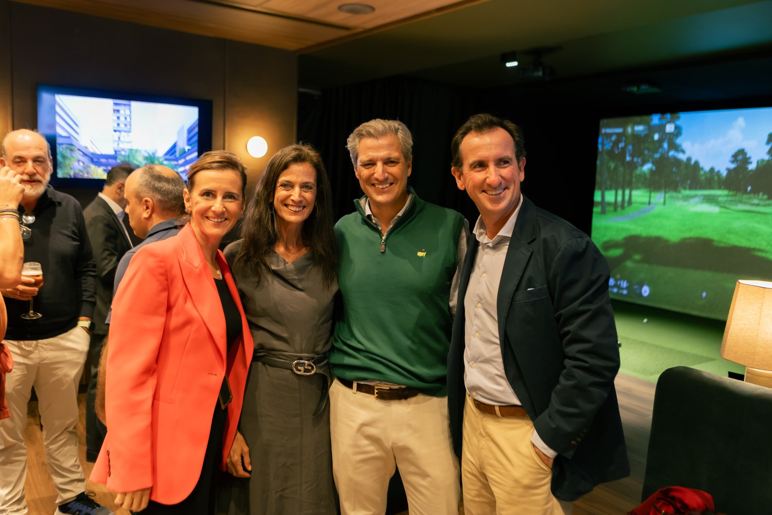 Cuatro invitados posan sonrientes junto a la pantalla de un simulador de golf en Socket, Madrid